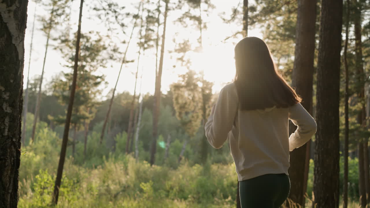 la mujer corredora disfruta del entrenamiento en el bosque al atardecer. la mujer activa hace una carrera nocturna pasando por los árboles bajo la cálida luz del sol. ejercicios de fitness para mejorar la forma del cuerpo