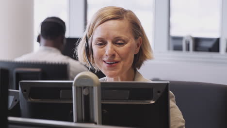 mujer de negocios madura que usa auriculares telefónicos hablando con la persona que llama en el departamento de servicios al cliente