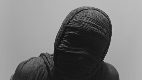 a mummy of a woman on a white backdrop rises her head