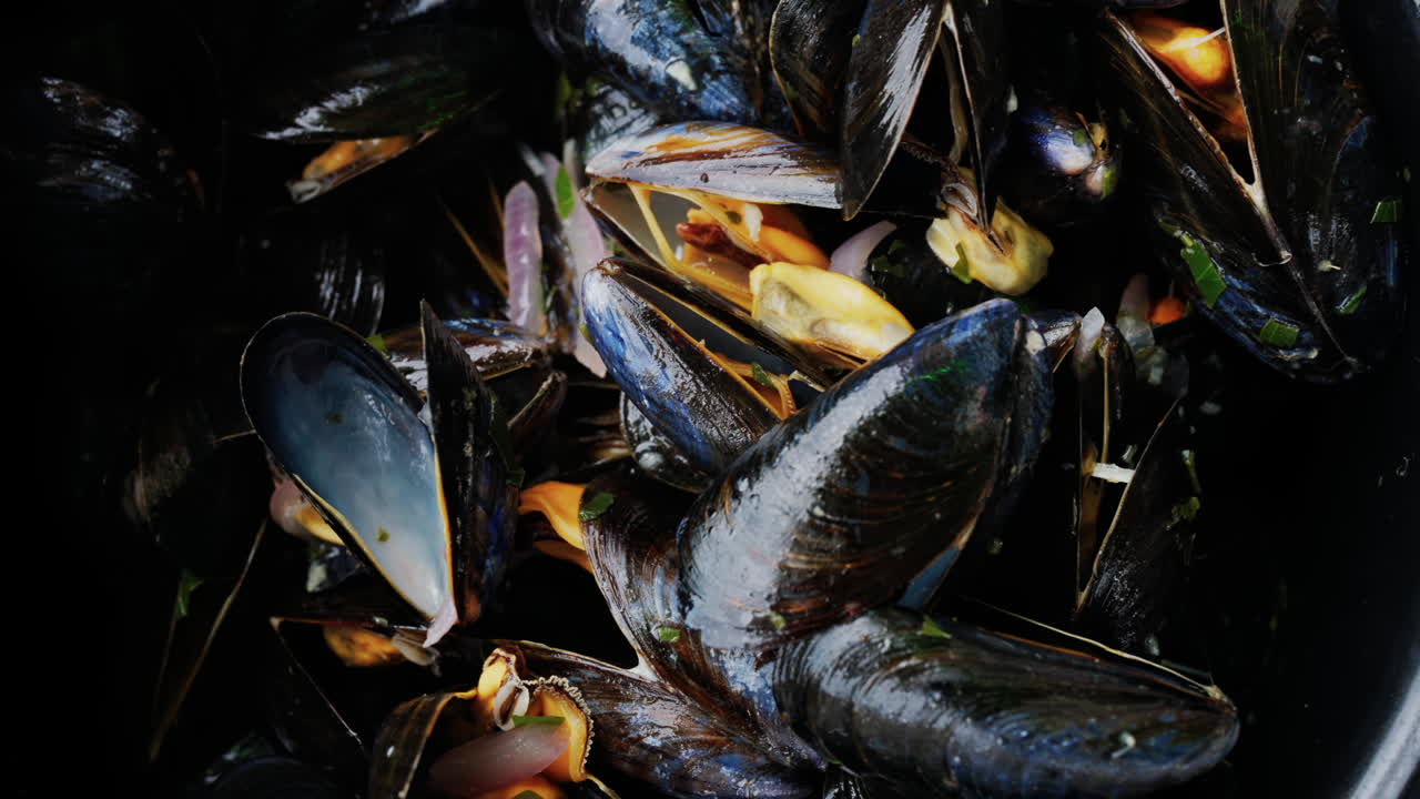 Close up of multiple steamy mussels in a pot