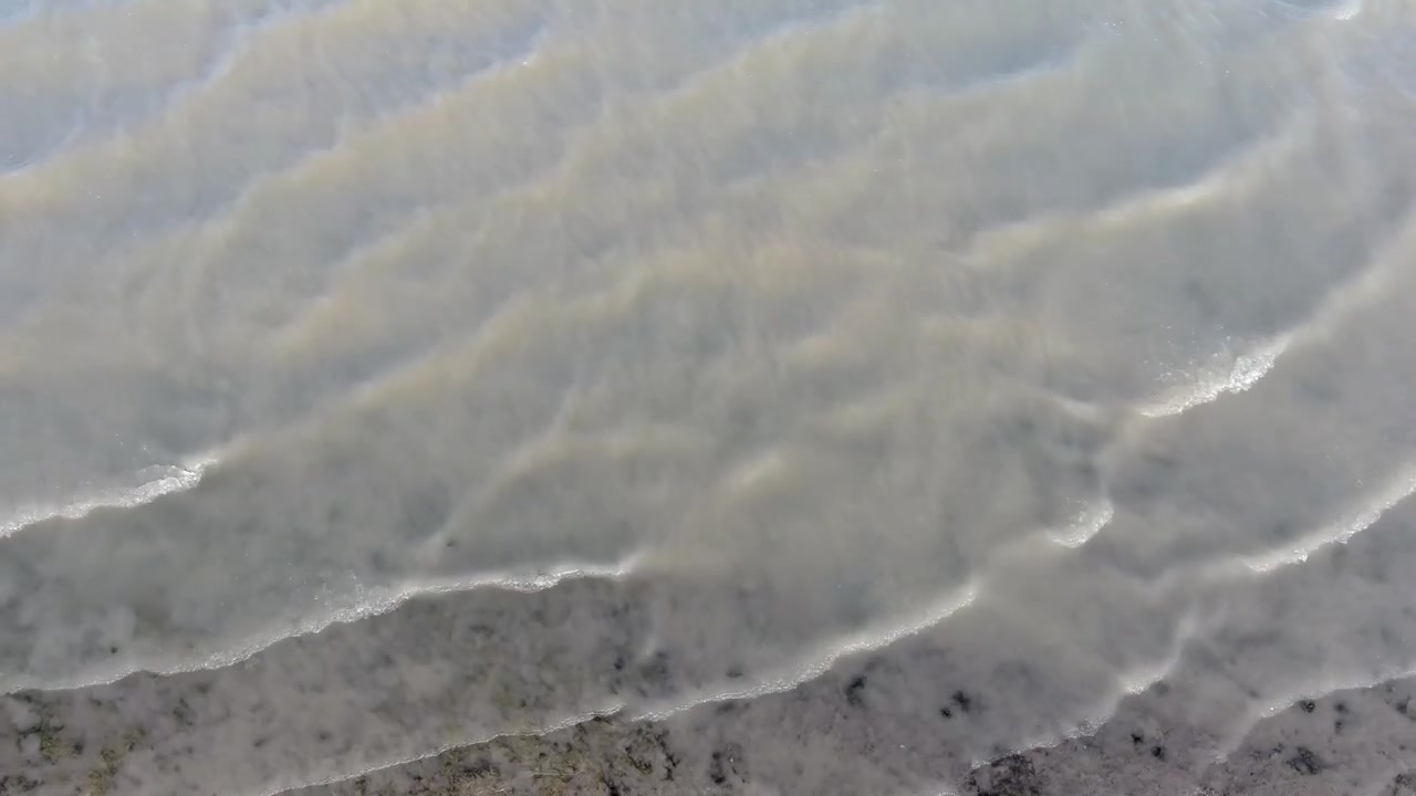 Aerial View of Gentle Waves Rolling onto a Sandy Shoreline