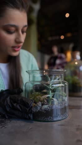 woman tending to a terrarium plant