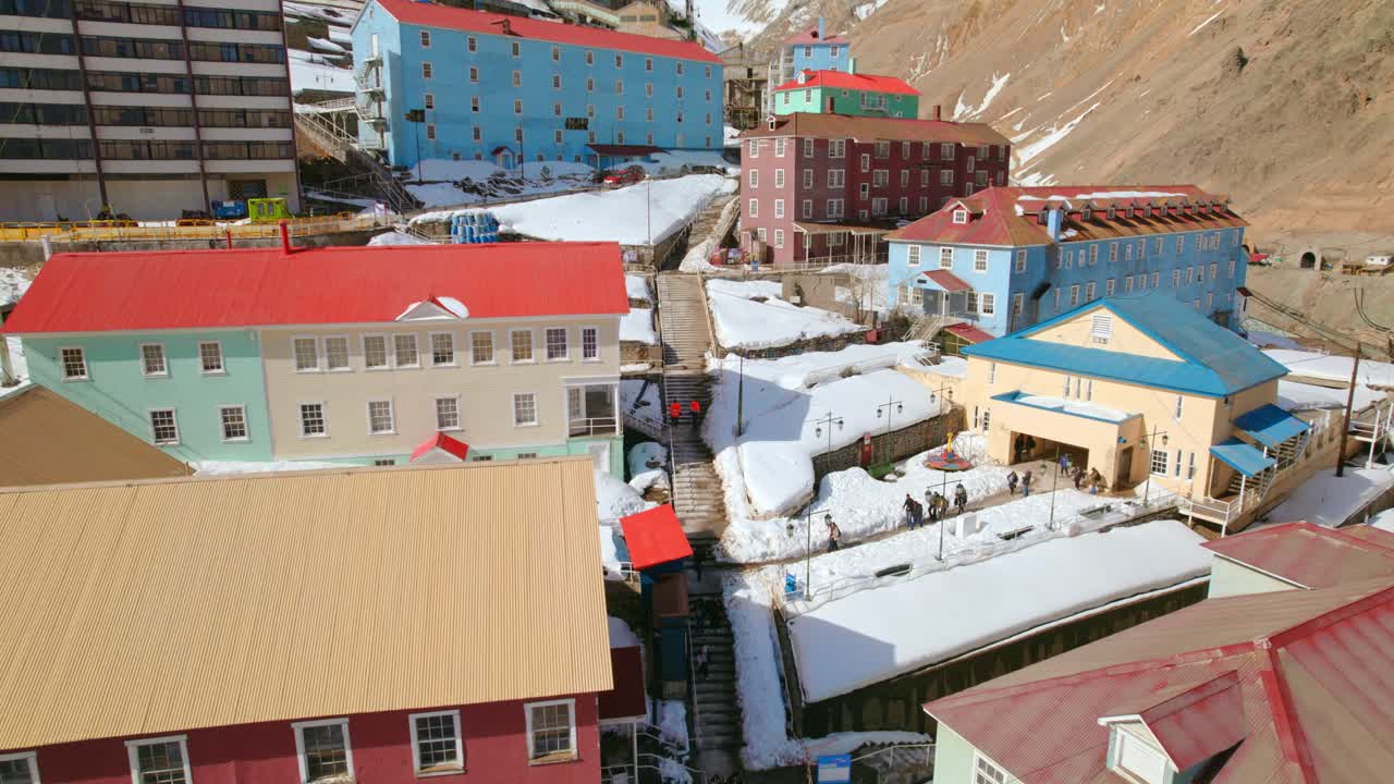 AERIAL: Tourists exploring the snowy Sewell town, La Ciudad de Las Escaleras, Chile