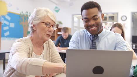 Senior female teacher helps student in adult education class