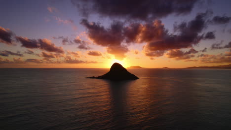 drone reveal shot of the sunrise behind china mans hat in hawaii