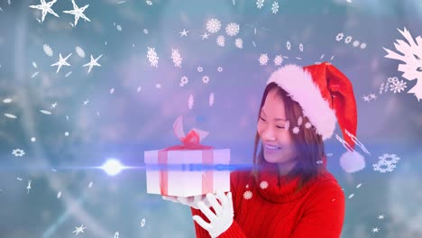Animation-Von-Schnee,-Der-über-Eine-Glückliche-Asiatische-Frau-Mit-Weihnachtsmütze-Fällt-Und-Geschenke-Hält