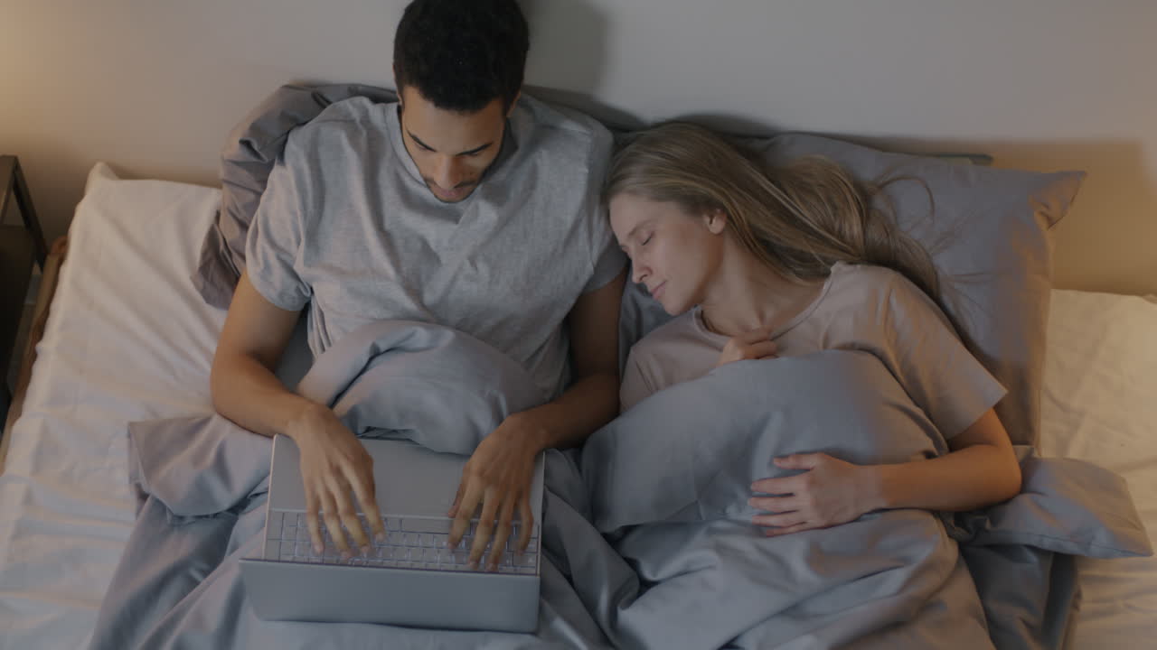 Coppia che lavora al laptop a letto di notte