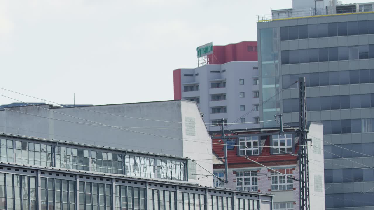 Modern high-speed train travels across elevated railway bridge in Berlin cityscape, daylight, static shot