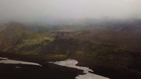 Aerial-landscape-view-of-mountains-with-snow-melting,-on-a-foggy-day,-Fimmvörðuháls-area,-Iceland