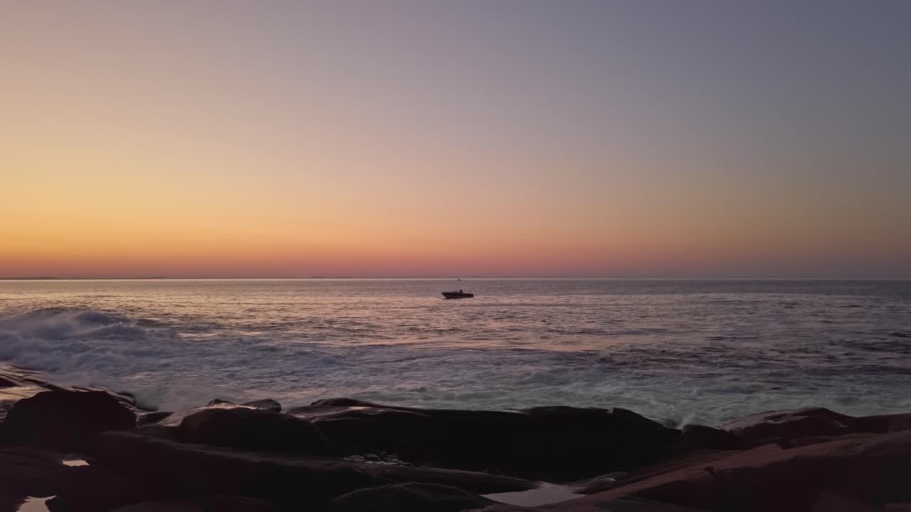 Floating boat on blue sea at purple sunset