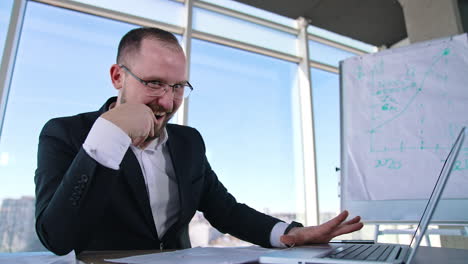 funny man in suit typing on a laptop. mad businessman in glasses working on a computer nervously in office room.
