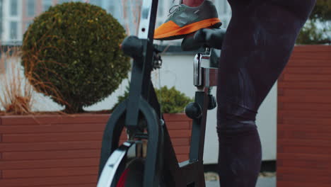 mujer atlética montando en una bicicleta estacionaria giratoria rutina de entrenamiento en el techo de la casa, pérdida de peso
