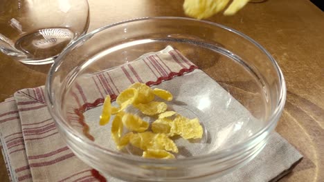 crispy yellow corn flakes into the bowl for the morning a delicious breakfast with milk. slow motion with rotation tracking shot.