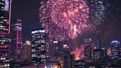 fireworks bursting over brightly lit skyscrapers, celebrating new year's eve in a vibrant metropolis, creating a magical display of color and excitement as the countdown to midnight unfolds