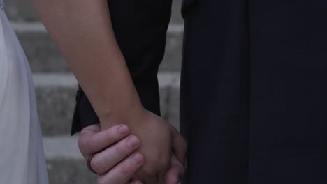 close up newlywed couple holding hands walking up stone church steps to wedding ceremony