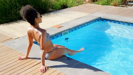 high angle view of young mixed-race woman relaxing at poolside on a sunny day 4k