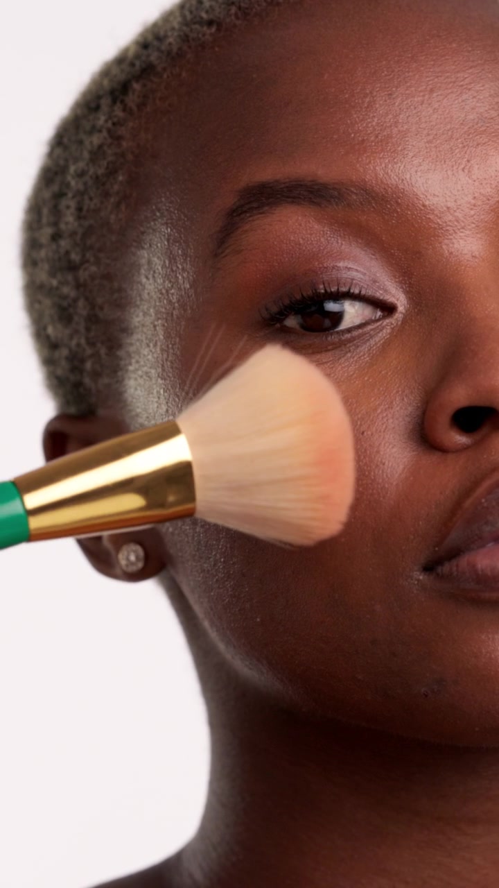 Close-up seorang wanita mengaplikasikan blush dengan kuas rias