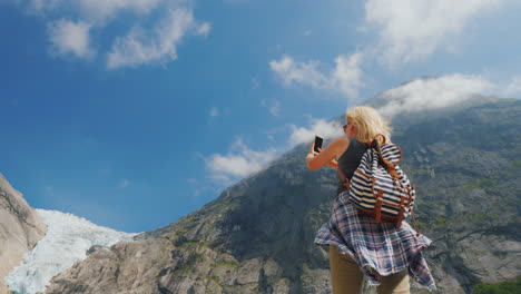 una joven activa toma fotografías del famoso glaciar riksdal lugares populares y famosos de noruega