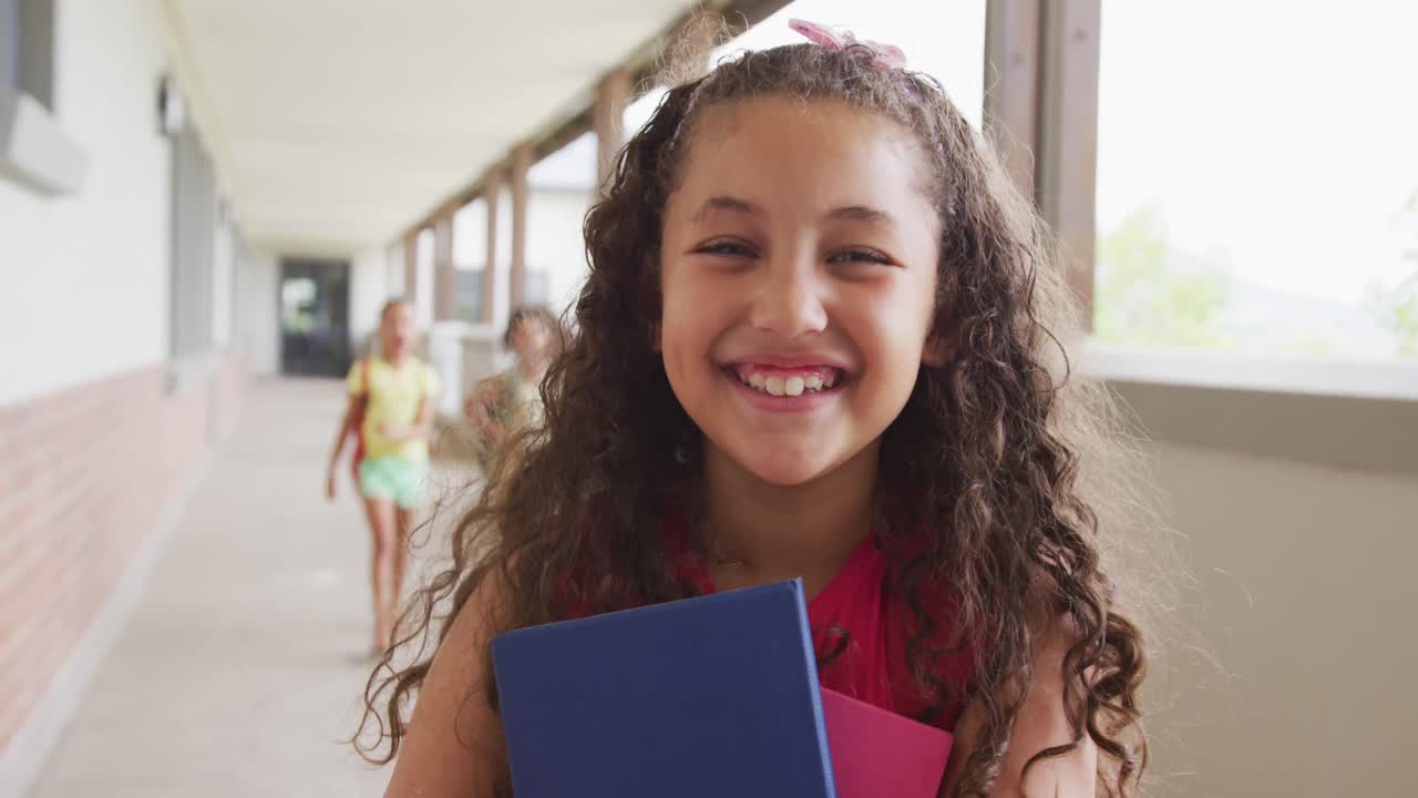 Video de chica birracial feliz de pie en el pasillo de la escuela
