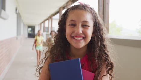 video de una chica biracial feliz de pie en el pasillo de la escuela