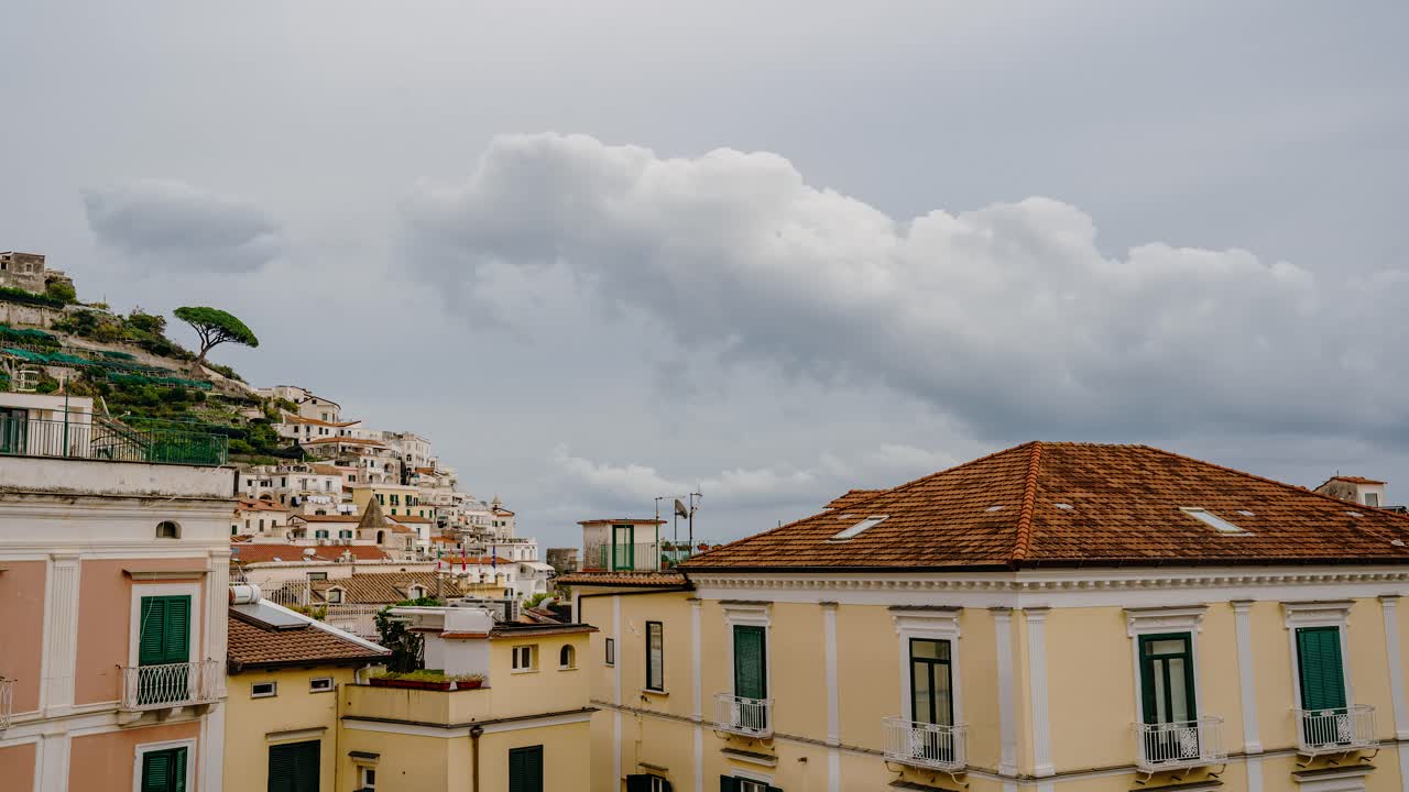 Timelapse di nuvole su una storica città italiana lungo la Costiera Amalfitana. Drammatico timelapse meteorologico sopra la storica città di Amalfi con nuvole in rapido movimento. Viaggio attraverso l'Italia.
