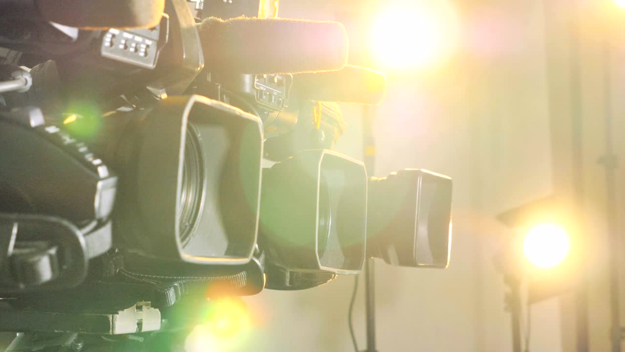 tres cámaras de video brillantemente iluminadas por focos.