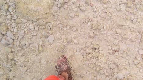 tipo caminando con sandalias bajo aguas cristalinas con rocas arenosas en la costa de los cayos de florida