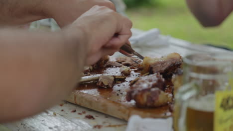 la gente disfruta comiendo pedazos de carne de la tabla de corte en la mesa de picnic en el parque