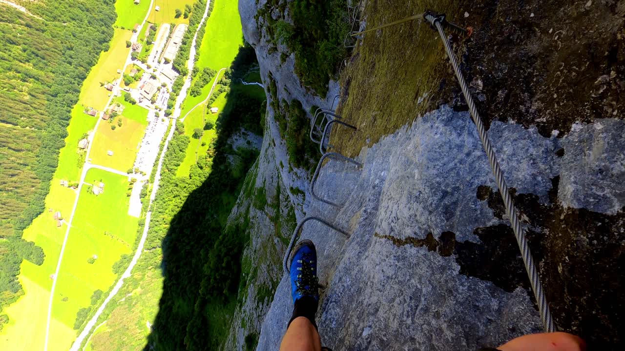 Seorang pria berjalan menuruni tangga logam di sepanjang via ferrata di Lauterbrunnen, Swiss