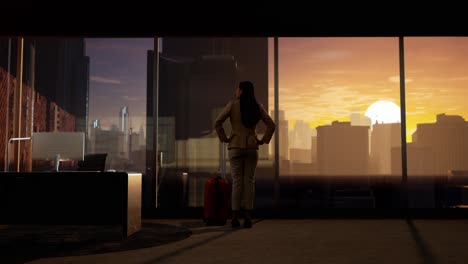 asian businesswoman with arms akimbo and looking out of the window on big city with skyscrapers at sunset
