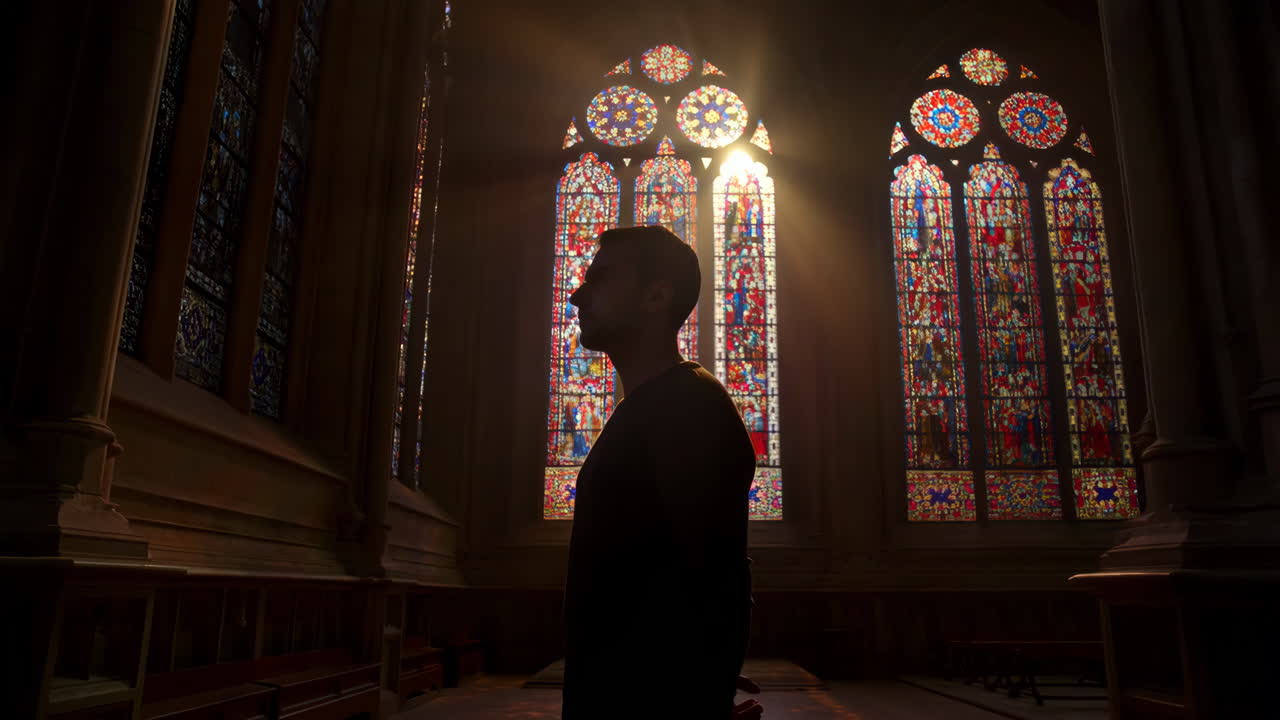 Silhouette of a man illuminated by sunlight through stained glass windows in a church
