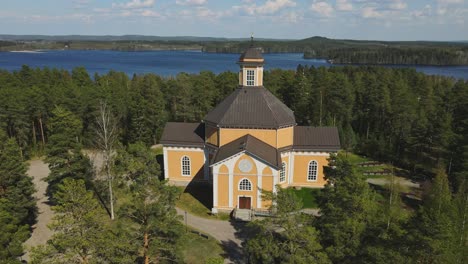 iglesia laukaa, finlandia, dolly out toma de drone de la vieja iglesia de madera en medio de lagos y bosques en un hermoso día de verano