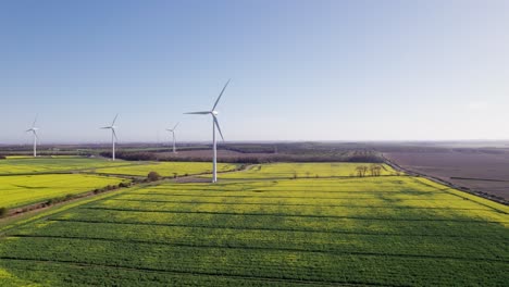 Drohnenschuss-Links-Von-Windkraftanlagen-An-Einem-Sonnigen-Tag,-Breit,-Aus-Der-Luft