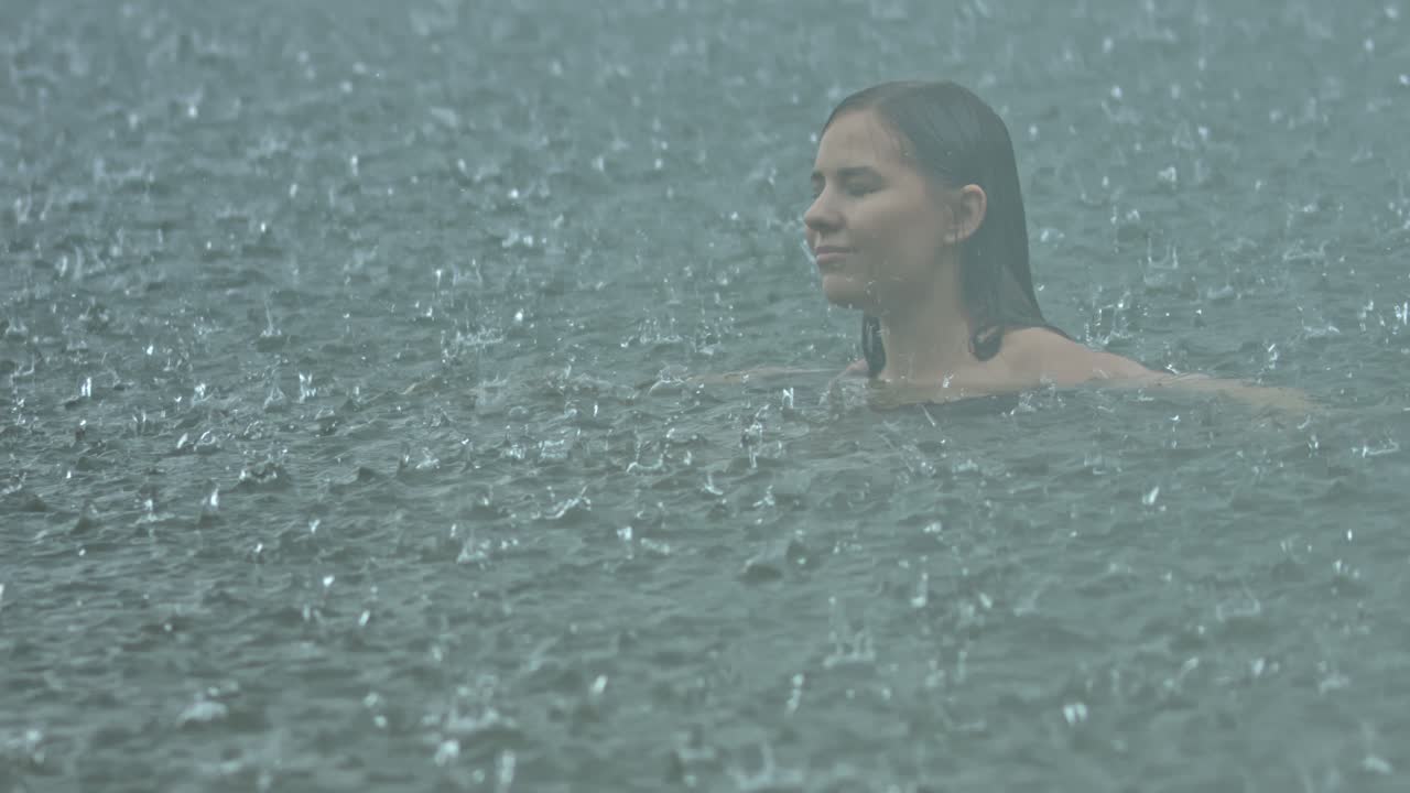 mujer nadando en el lago bajo la lluvia de verano