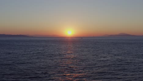 aerial - flying sideways over the sea at sunset