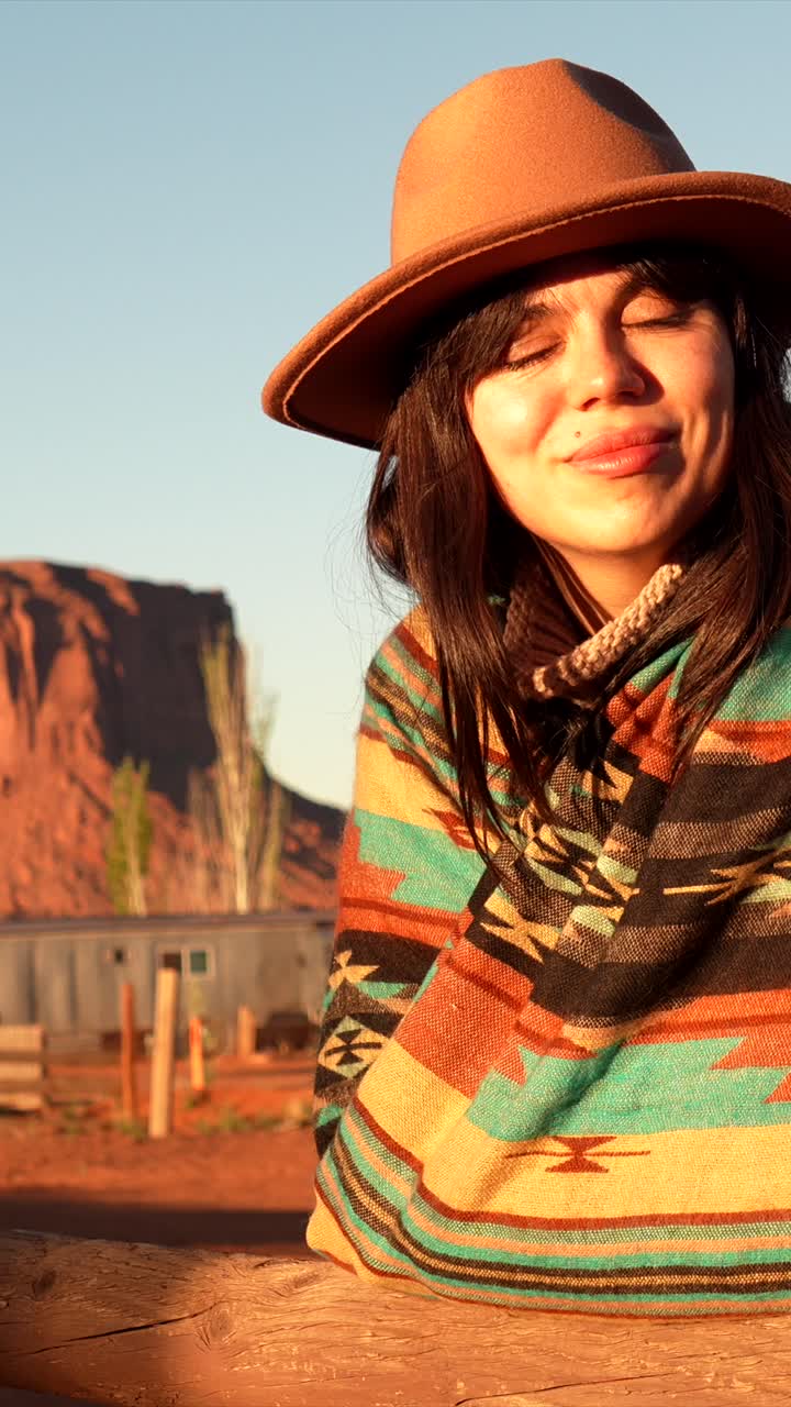 Donna felice con cappello e poncho che si gode la luce del tramonto nel deserto
