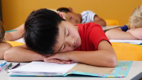 school kids sleeping on desk in classroom