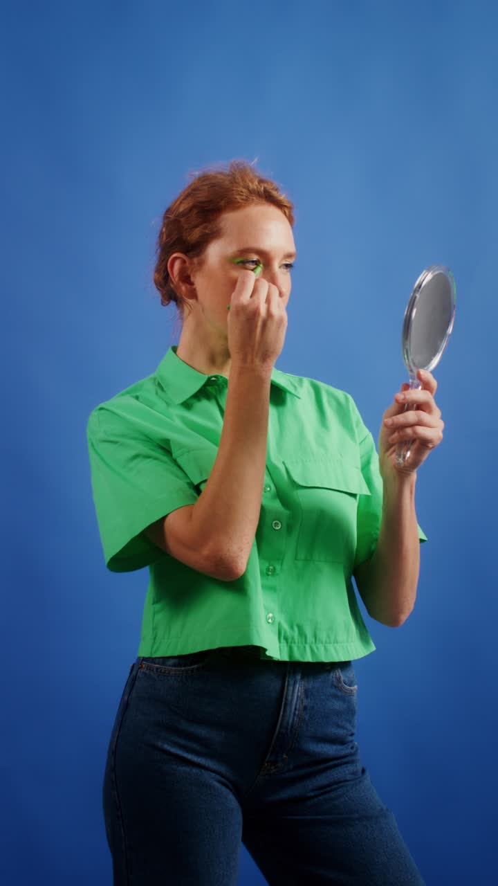 Woman applying makeup while looking in a mirror