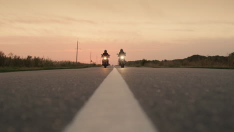 Silhouettes-of-two-motorcyclists-quickly-pass-by-the-camera