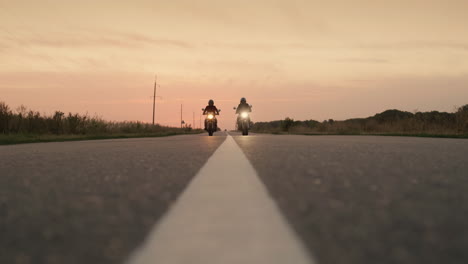 silhouettes of two motorcyclists quickly pass by the camera