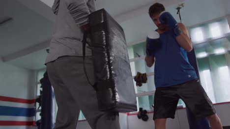 hombre caucásico entrenando con el entrenador en el gimnasio de boxeo