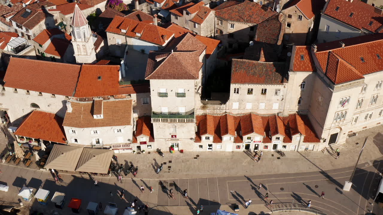 Widok z lotu ptaka na ludzi spacerujących po promenadzie z wenecką architekturą na Starym Mieście Trogiru w Chorwacji latem