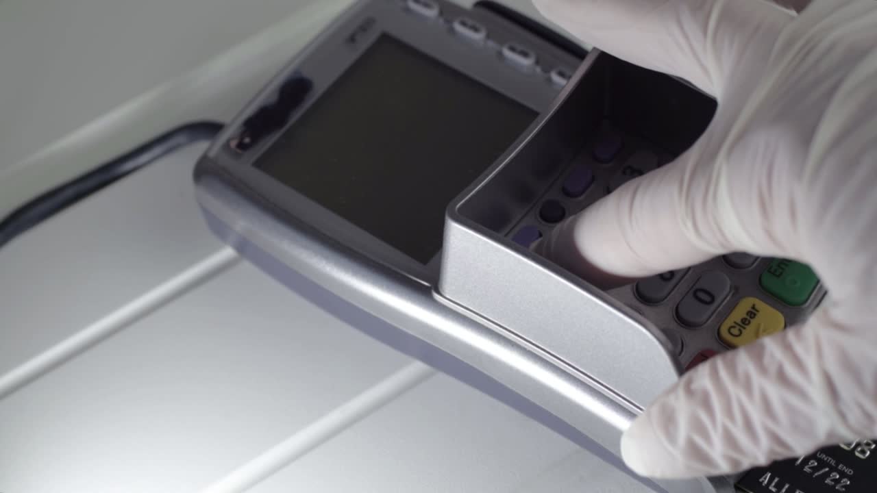 Hand wearing hygienic gloves using pdq payment machine medium shot