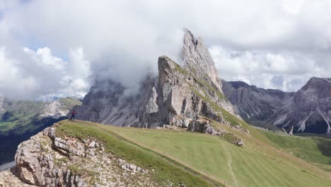 persona en la cima de la montaña volando drones filmando la épica cordillera después de caminar por la pista de la cresta de seceda en los dolomitas, italia