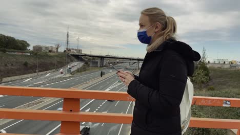 woman with mobile crossing the overpass