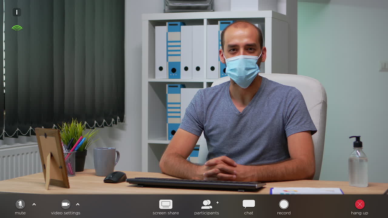 Lavoratore che indossa una mascherina e parla in telecamera.