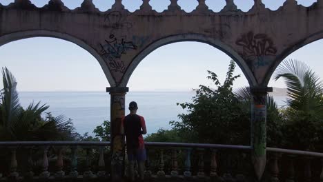 turista masculino en el miro, un antiguo hotel abandonado con vistas a la impresionante costa de jacó en costa rica