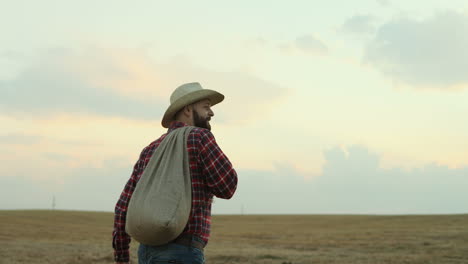 Back-view-on-the-farmer-man-wearing-a-red-shirt-and-a-hat