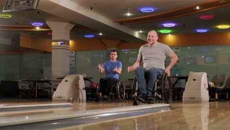 two young disabled men in wheelchairs playing bowling in the club
