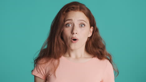 Redheaded-girl-in-front-of-camera-on-turquoise-background.